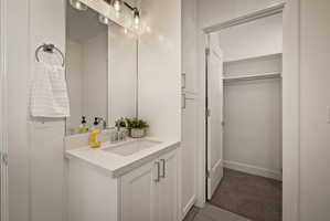 Bathroom with vanity, a walk in closet, dark tile patterned flooring, and dark carpet