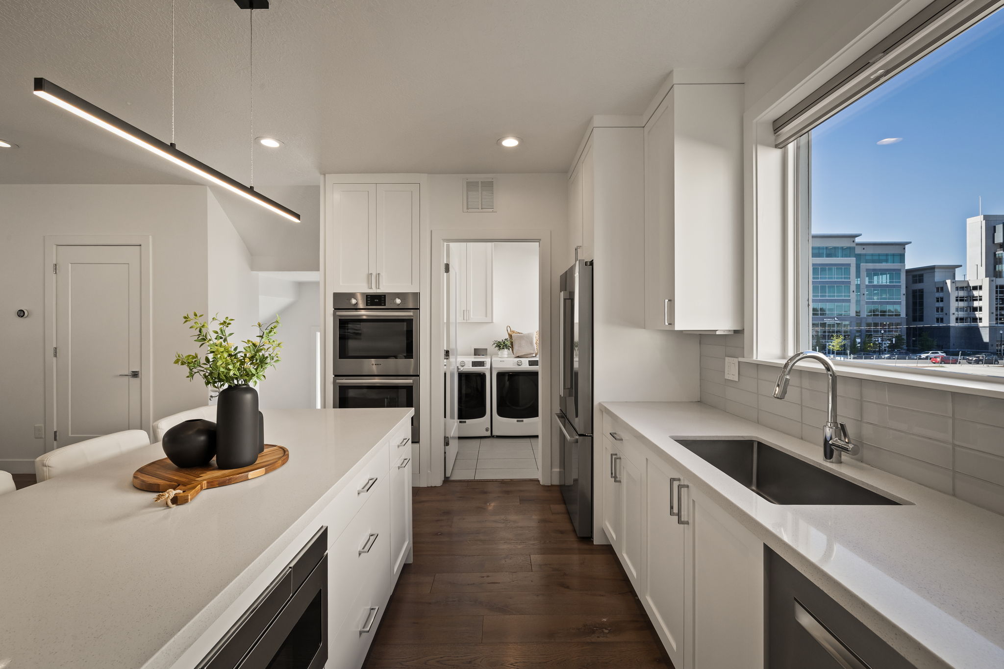 Kitchen with washer and clothes dryer, white cabinetry, stainless steel appliances, dark wood-style floors, and light stone countertops