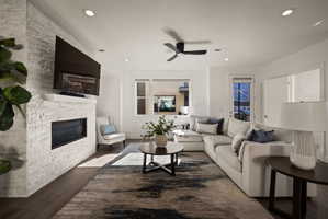 Living room featuring a fireplace, a ceiling fan, dark wood-type flooring, and recessed lighting