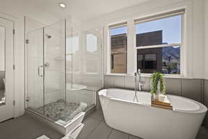 Full bath featuring a shower stall, a freestanding tub, light tile patterned floors, and recessed lighting