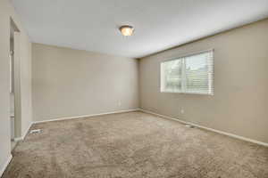 Carpeted room featuring a single window with blinds, a ceiling-mounted light fixture, and neutral-toned walls