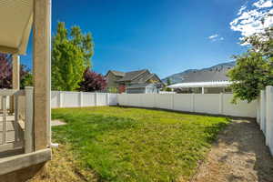 Expansive backyard featuring a white vinyl privacy fence and a manicured lawn
