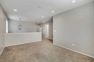Carpeted interior area with recessed lighting, a decorative pendant fixture, and neutral wall tones