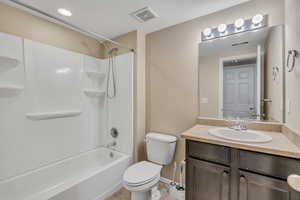 Bathroom featuring a white tub/shower combination, dark wood vanity with a light-colored countertop, integrated sink, and an overhead vanity light fixture