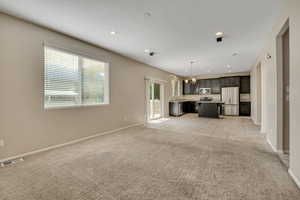Open-concept living area with neutral carpeting and recessed lighting