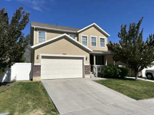 Two-story residence featuring a stucco exterior with brick accents and a prominent two-car garage