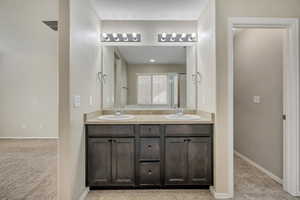 Dual vanity featuring dark wood cabinetry, integrated sinks, and individual wall-mounted light fixtures