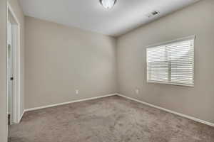 Neutral tone walls complemented by a single window with horizontal blinds, overhead flush mount lighting, and gray carpet flooring