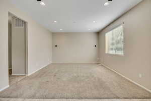 Spacious room featuring neutral wall tones, recessed ceiling lighting, and a large window with blinds