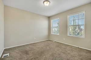 Carpeted interior space featuring two windows with horizontal blinds, neutral wall paint, and a semi-flush mount ceiling light fixture
