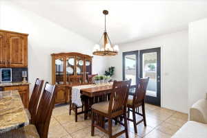 Dining area featuring vaulted ceilings, a wood-finish chandelier, and tile flooring