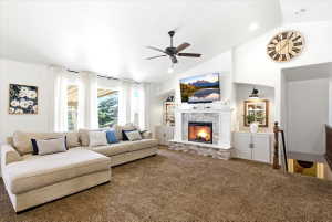 Vaulted ceiling living area featuring a stone fireplace, shiplap accent wall, built-in cabinetry, and multiple windows