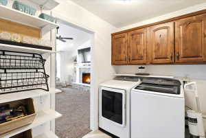 Laundry area and pantry space featuring wood cabinetry, white appliances, and a light-toned tile floor