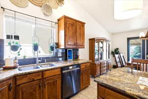 Kitchen featuring rich wood cabinetry, granite countertops, a stainless steel double basin sink, and a matching stainless steel dishwasher