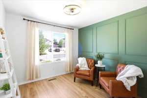 Main floor bedroom 2 - Hardwood-finish flooring complements a distinctive green accent wall with decorative panel molding