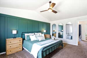 Primary Bedroom - Vaulted ceiling featuring a ceiling fan, accent wall with panel detailing, and neutral-toned carpeting