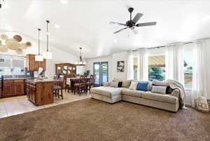 Vaulted ceilings highlight this open-concept living area featuring a kitchen with stained wood cabinetry and a central island, a dedicated dining space, and large windows