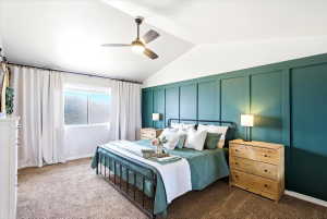 Vaulted ceiling bedroom featuring a window with natural light, a ceiling fan, a board and batten accent wall, and carpeting
