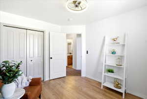 Main floor bedroom 2 - Bright room featuring wood-finish flooring, white walls, and a contemporary ceiling fan with integrated lighting