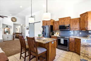 Kitchen featuring wood cabinetry, stainless steel appliances, granite countertops, and a tiled backsplash