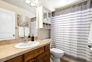 Main Floor Guest Bathroom vanity featuring a wood-finish cabinet, laminate countertop, and an undermount sink with a chrome faucet