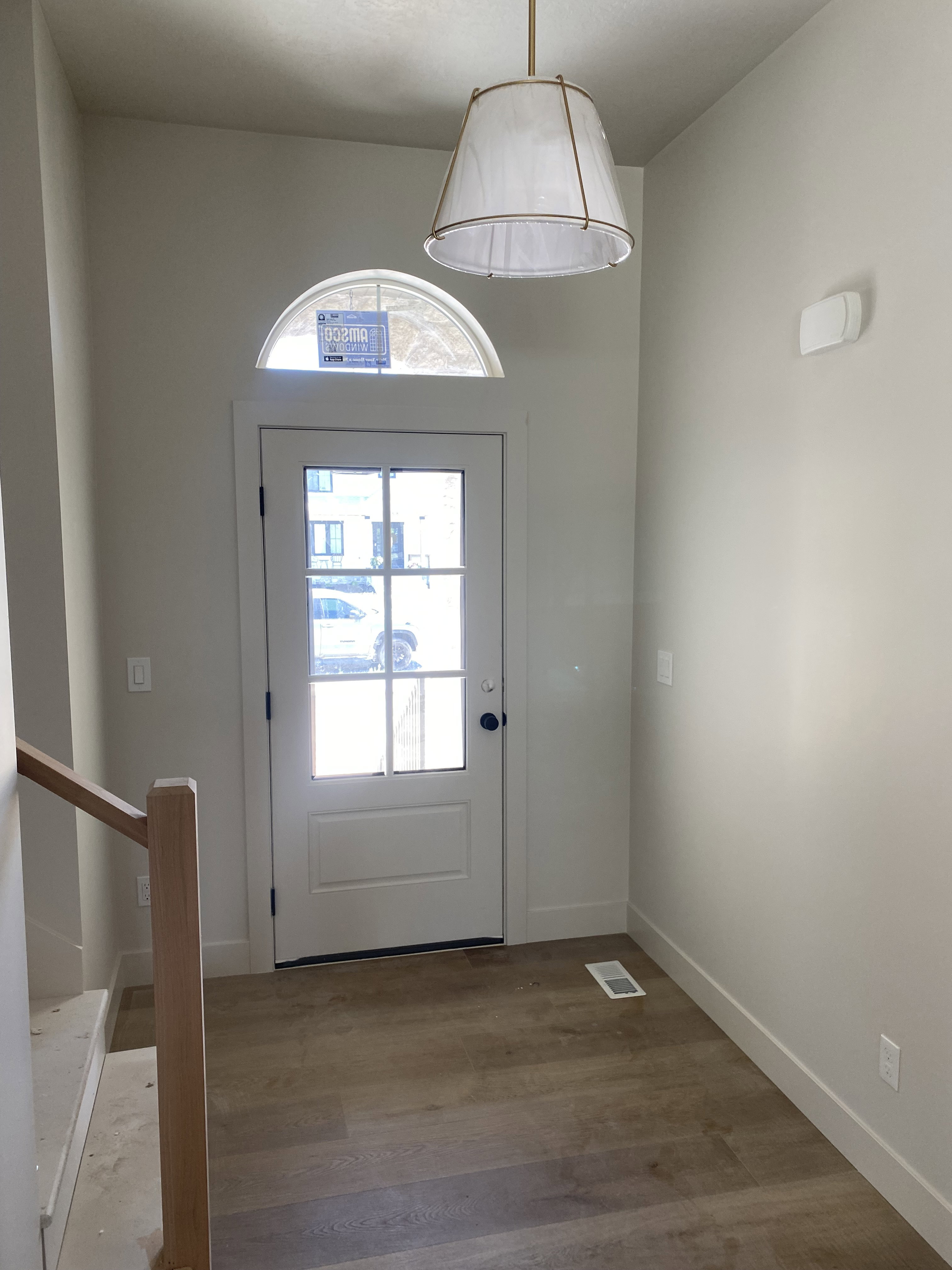 Entryway featuring a glass-paneled door with an arched transom window, wood-finish flooring, and a contemporary pendant light fixture