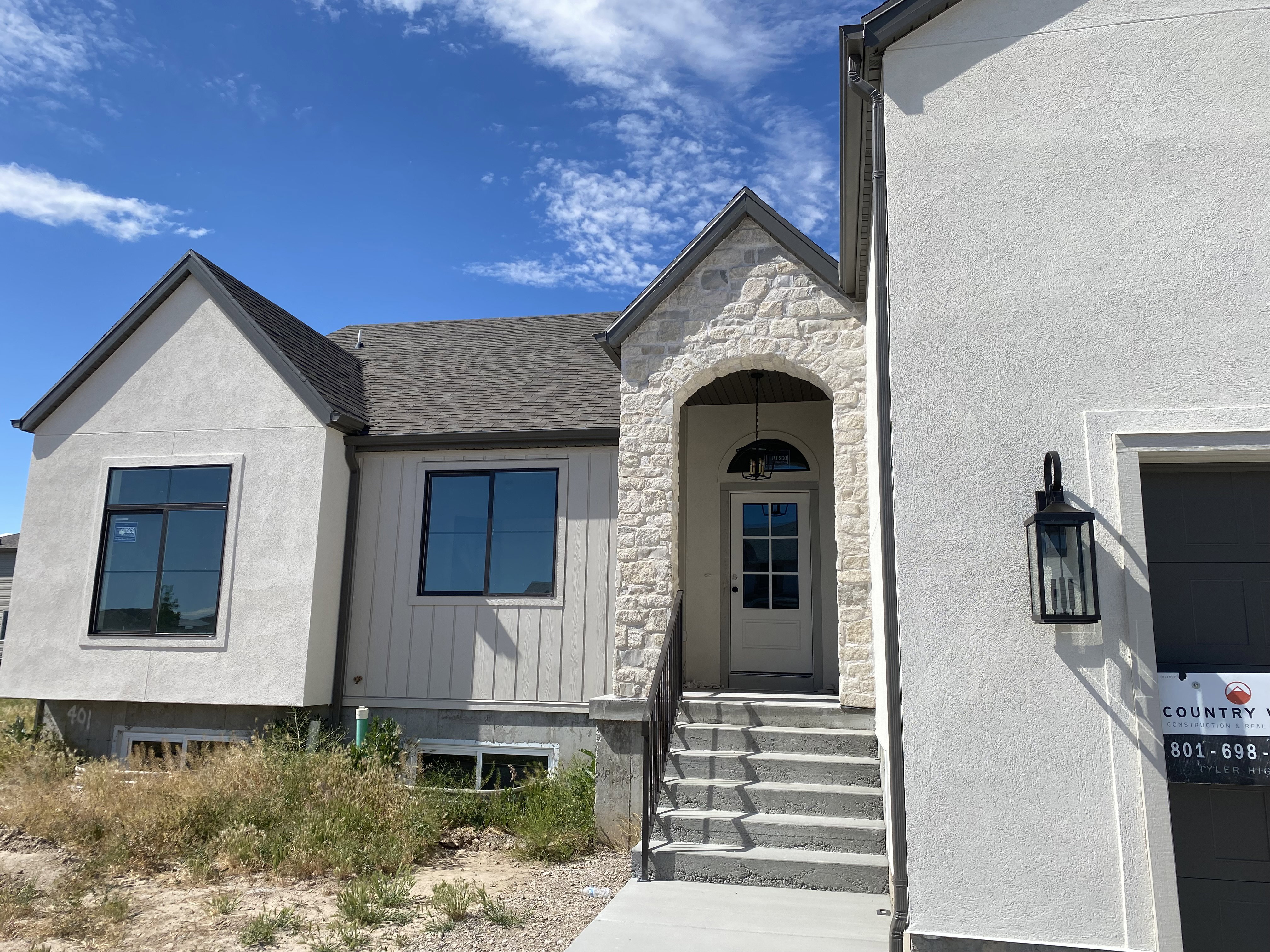 Exterior featuring a stone-clad entry arch and a paneled front door with an arched transom