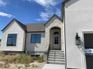 Exterior featuring a stone-clad entry arch and a paneled front door with an arched transom