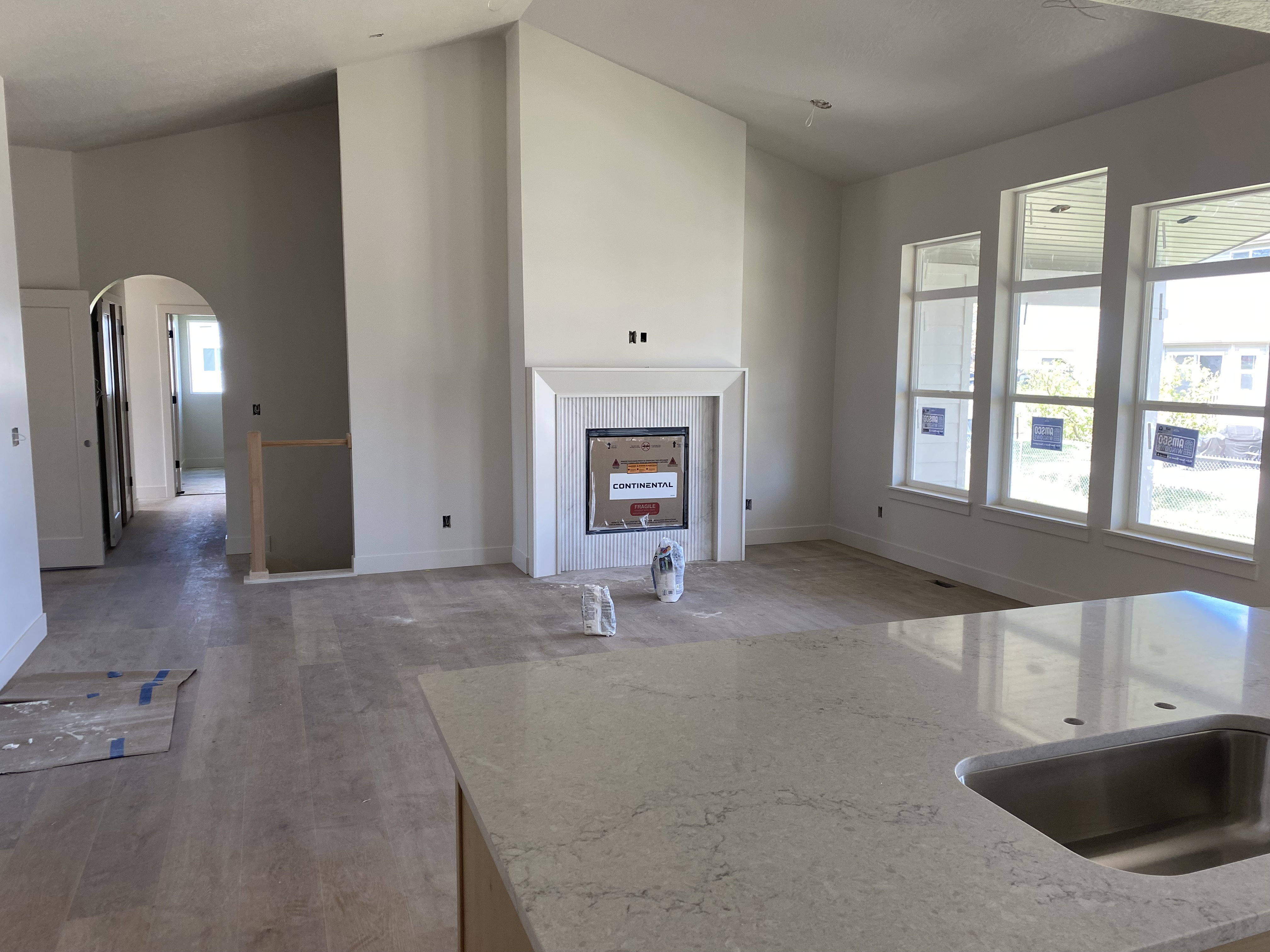 Spacious living area featuring a vaulted ceiling and a fireplace with a white mantel and tile surround