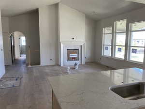 Spacious living area featuring a vaulted ceiling and a fireplace with a white mantel and tile surround