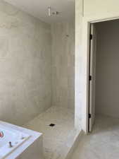 Tiled walk-in shower with a low-curb entry, featuring large format marble-look wall tiles and a hexagonal mosaic floor
