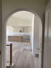 Arched doorway opening to an open-concept living space with wood-finish flooring