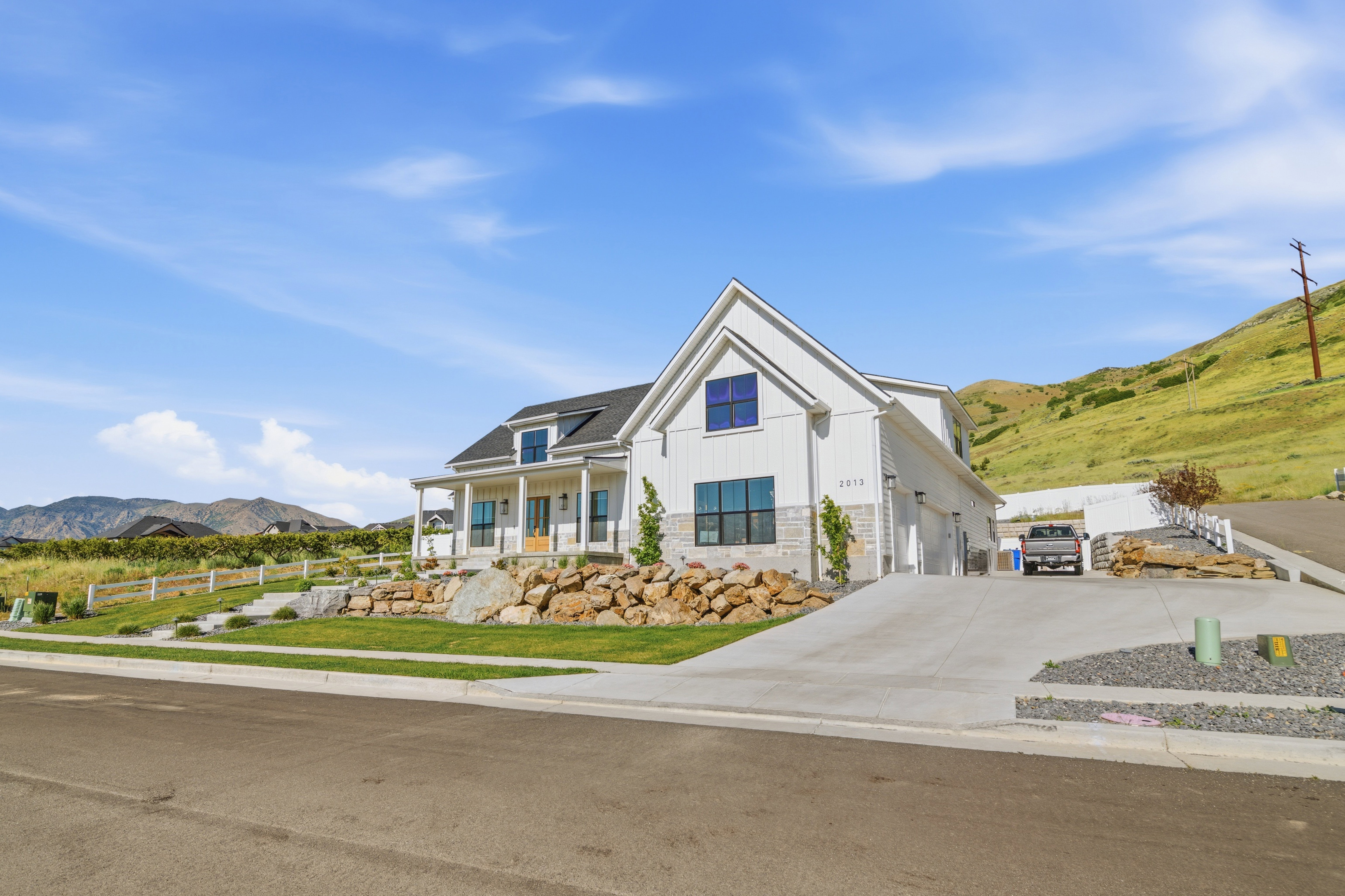 Modern farmhouse style residence featuring white vertical siding, a black shingle roof, and dark-framed windows