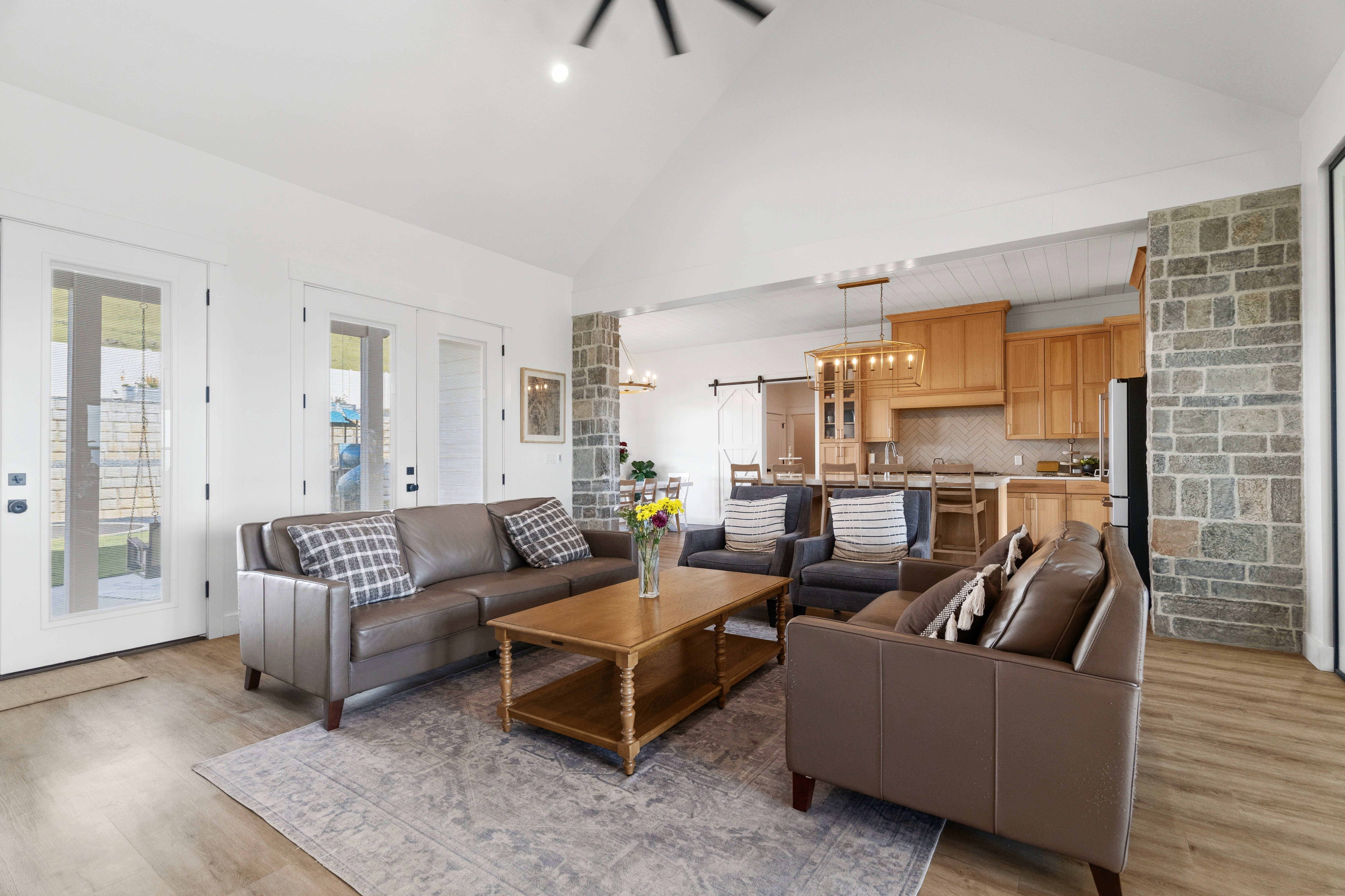 Vaulted ceilings highlight this living area featuring wood-finish flooring and multiple glass-paned doors