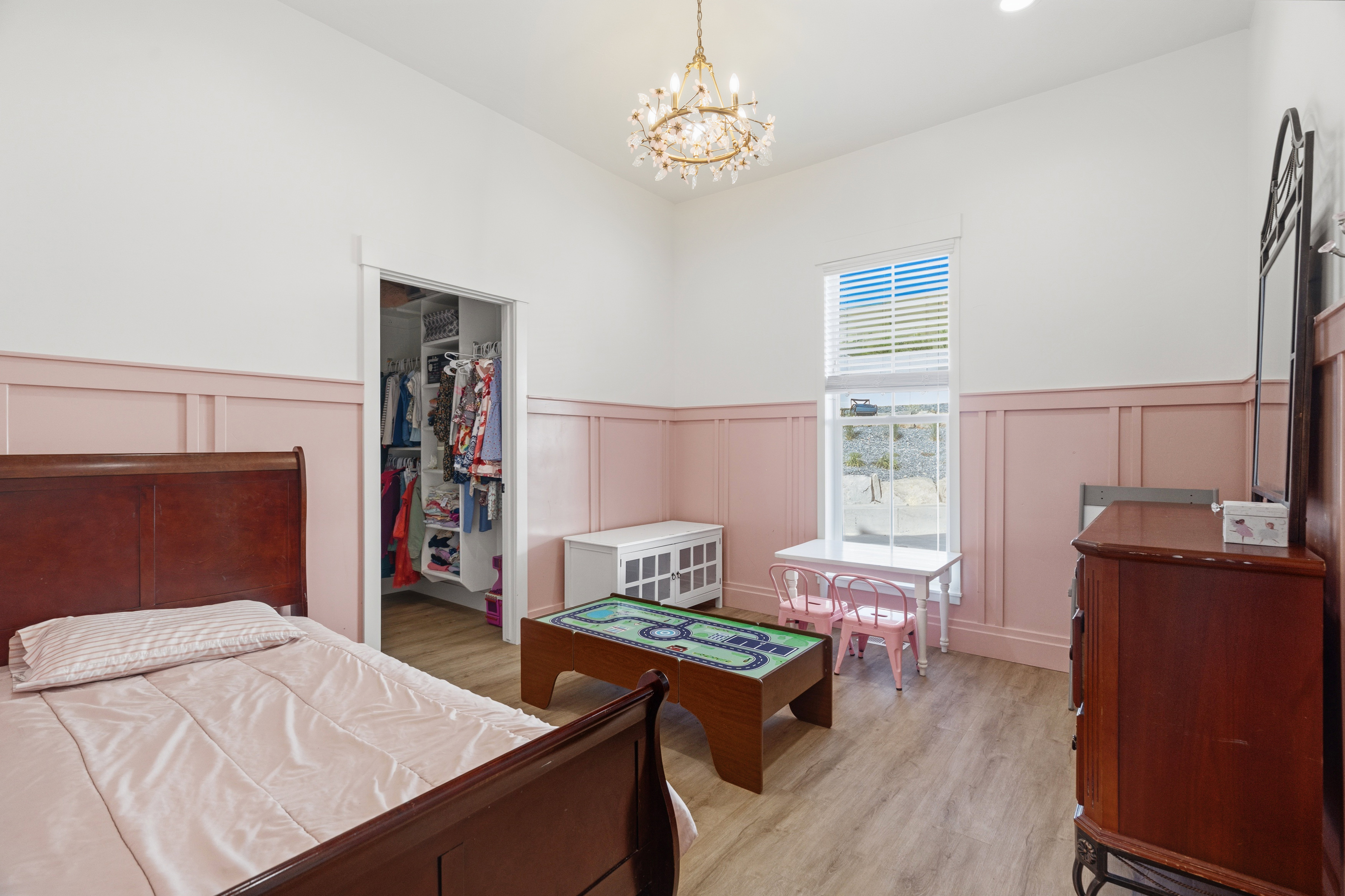 Spacious room featuring wood-finish flooring, a chandelier fixture, and a built-in closet with shelving