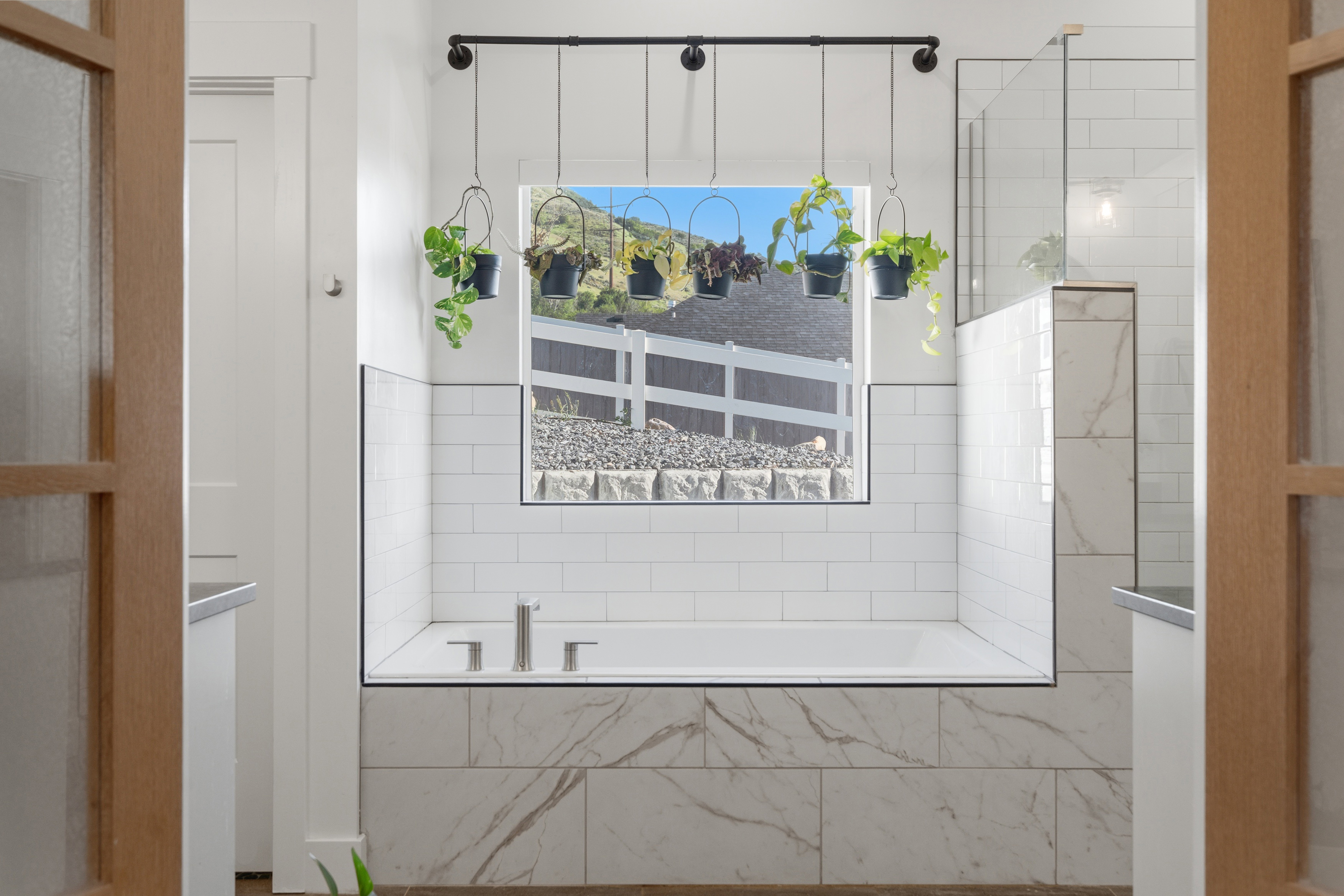 Soaking tub with subway tile surround, accented by a marble-look tile base