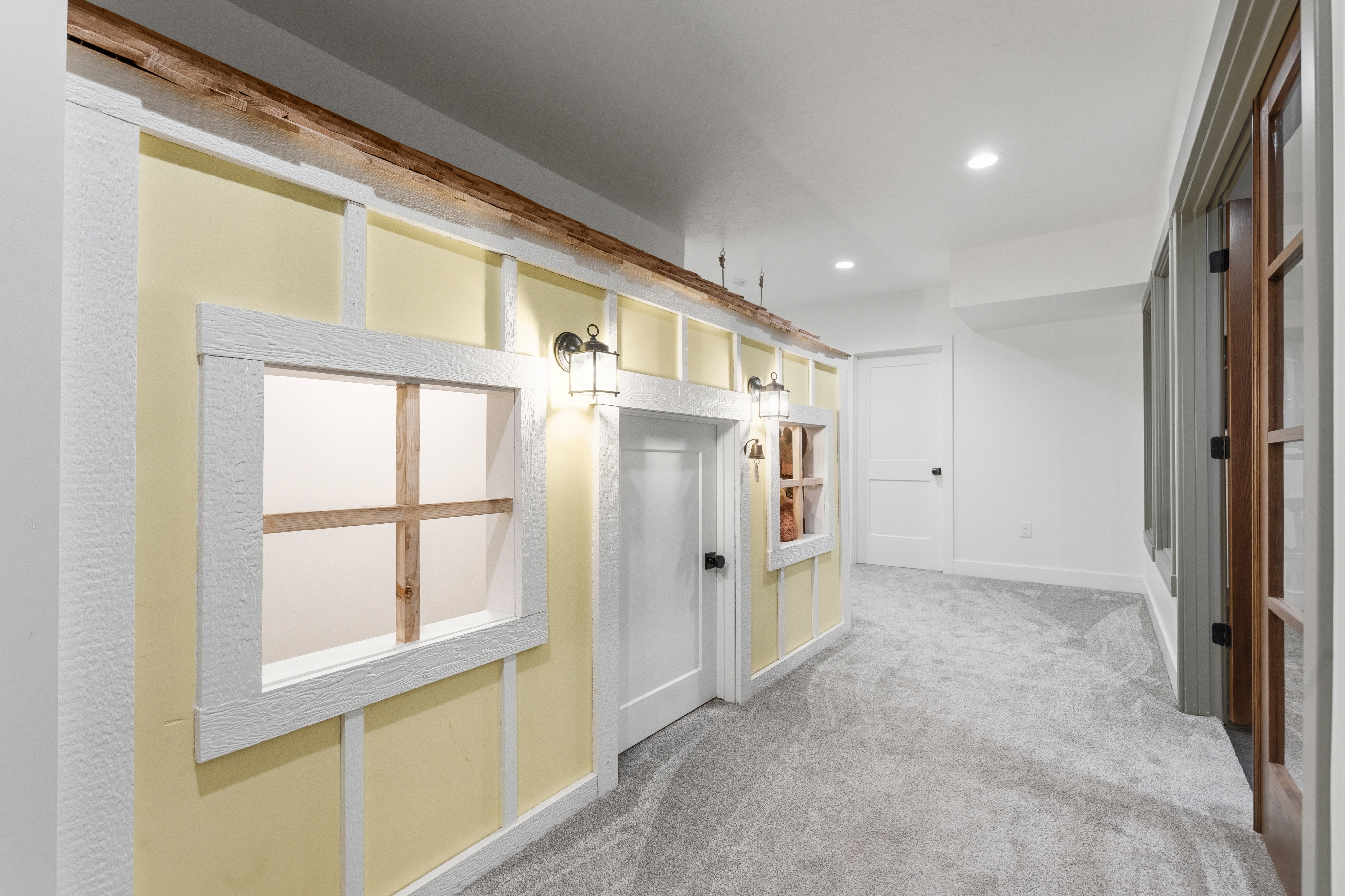 Hallway featuring light yellow walls with white trim, wood-look accents, recessed lighting, and grey carpeting