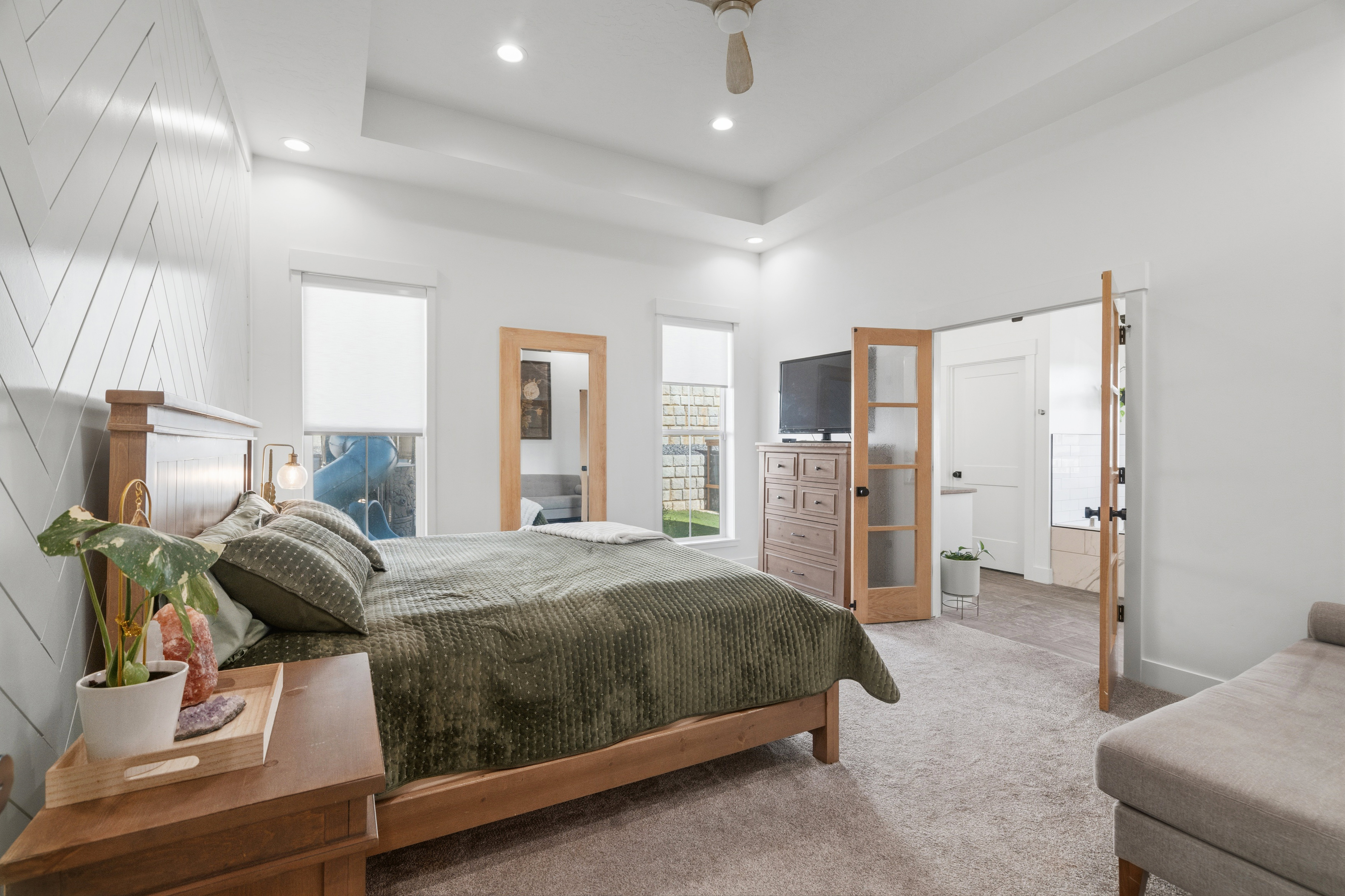 Bedroom featuring a tray ceiling with recessed lighting, wood-finish ceiling fan, and carpeted flooring