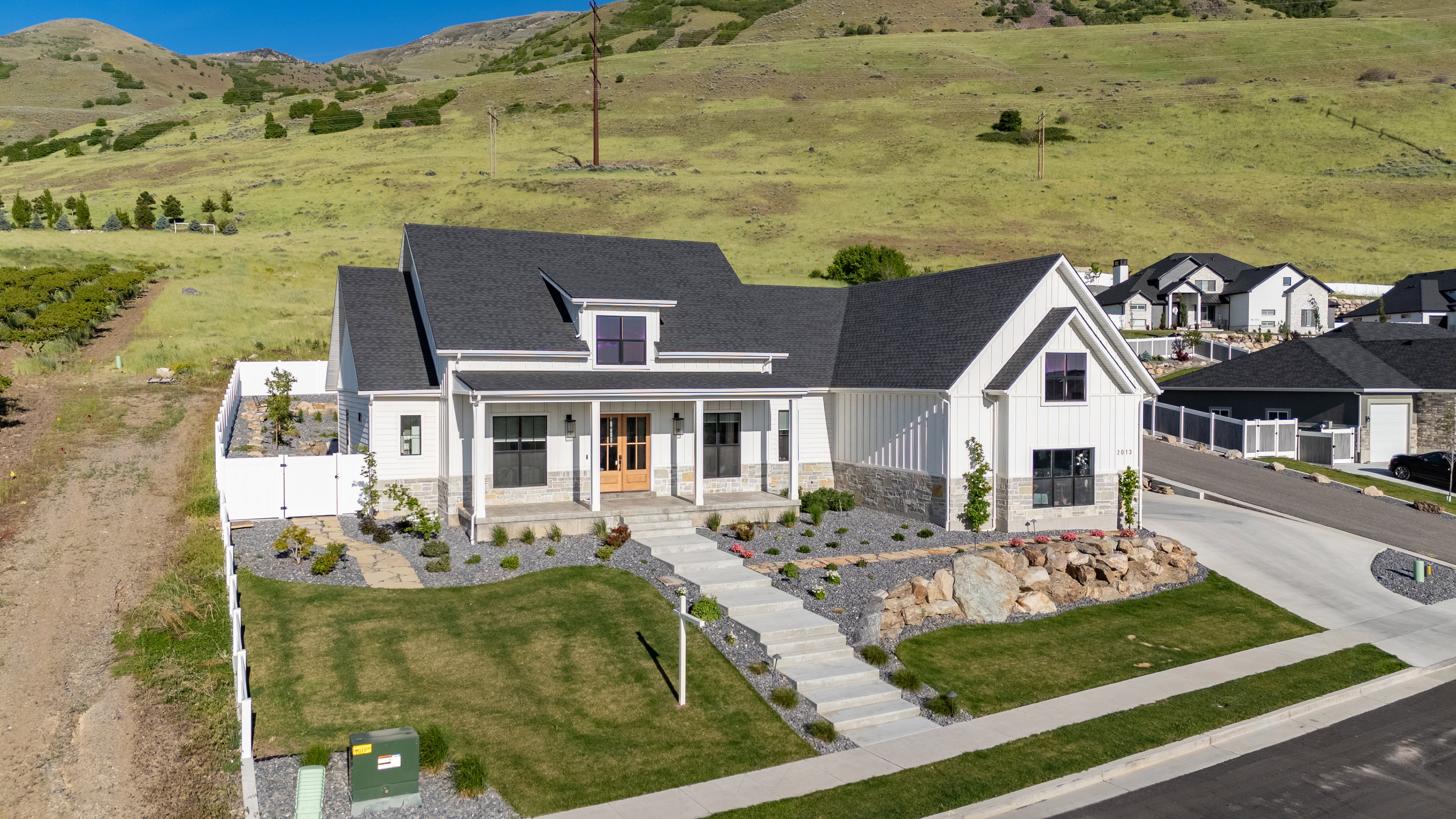 Modern farmhouse exterior featuring white board and batten siding, stone accents, and dark shingle roofing
