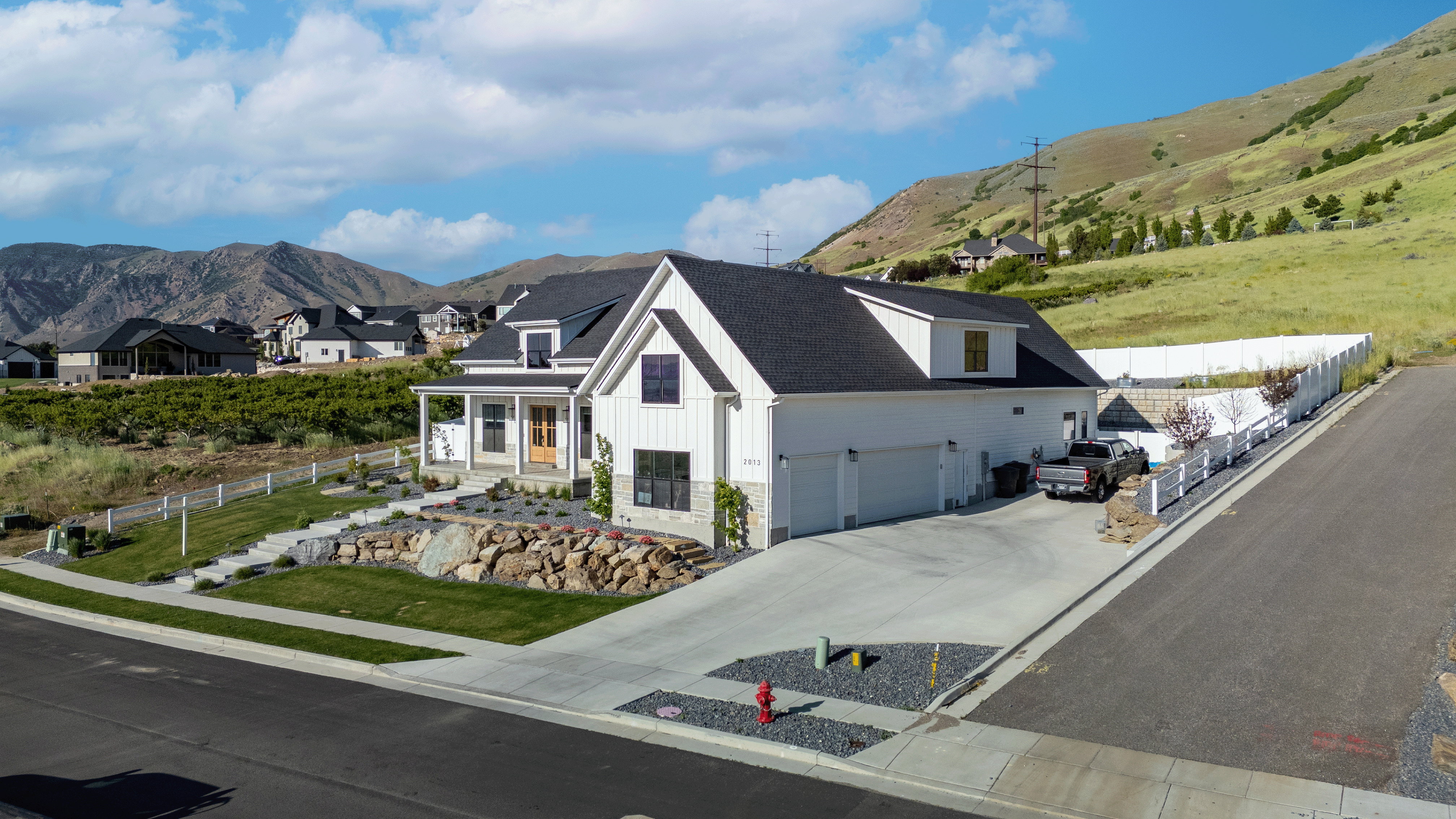 Contemporary farmhouse-style residence featuring a prominent gable roofline and white vertical siding