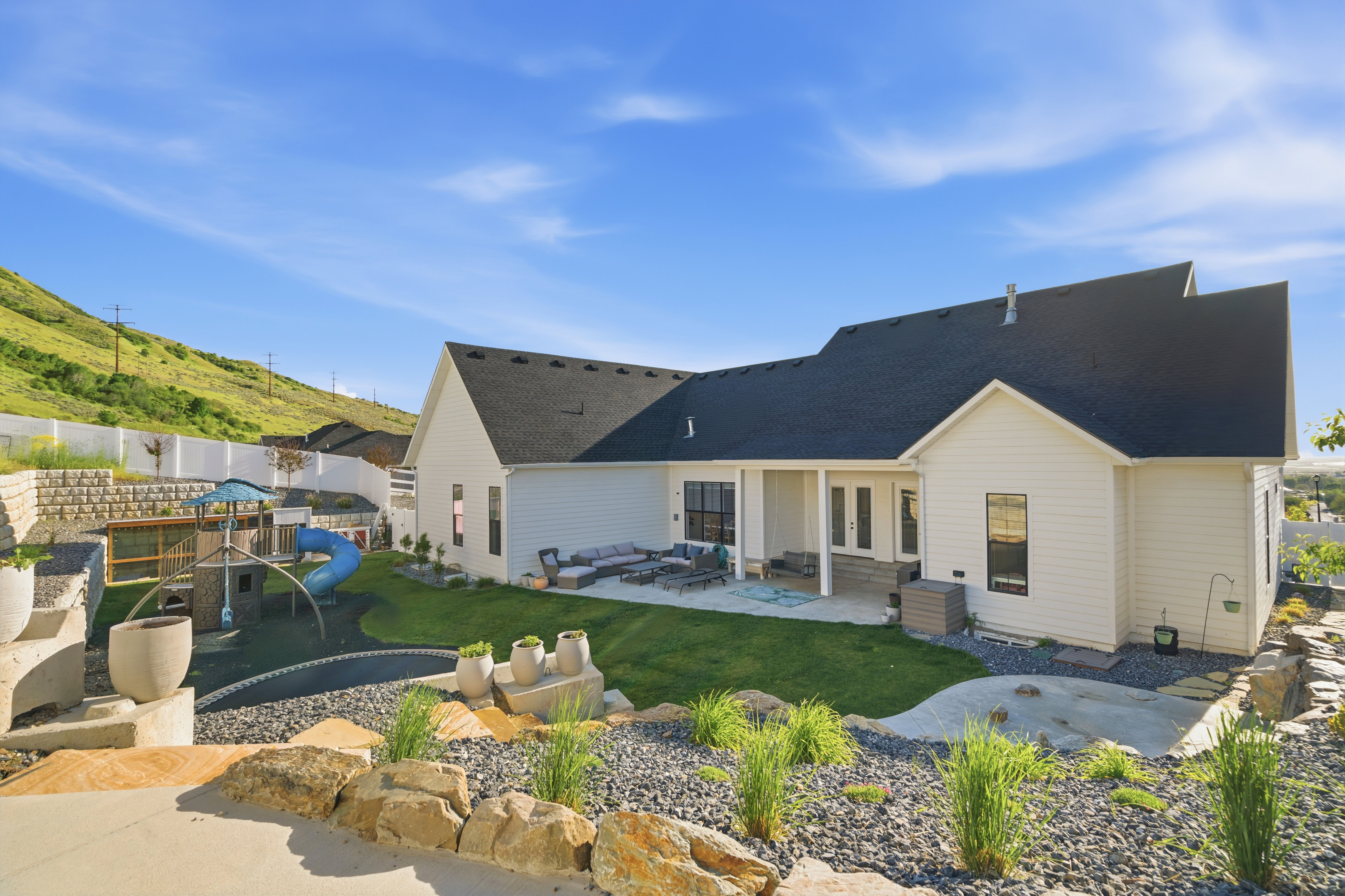 Expansive backyard featuring a manicured lawn, a built-in trampoline, and a terraced retaining wall