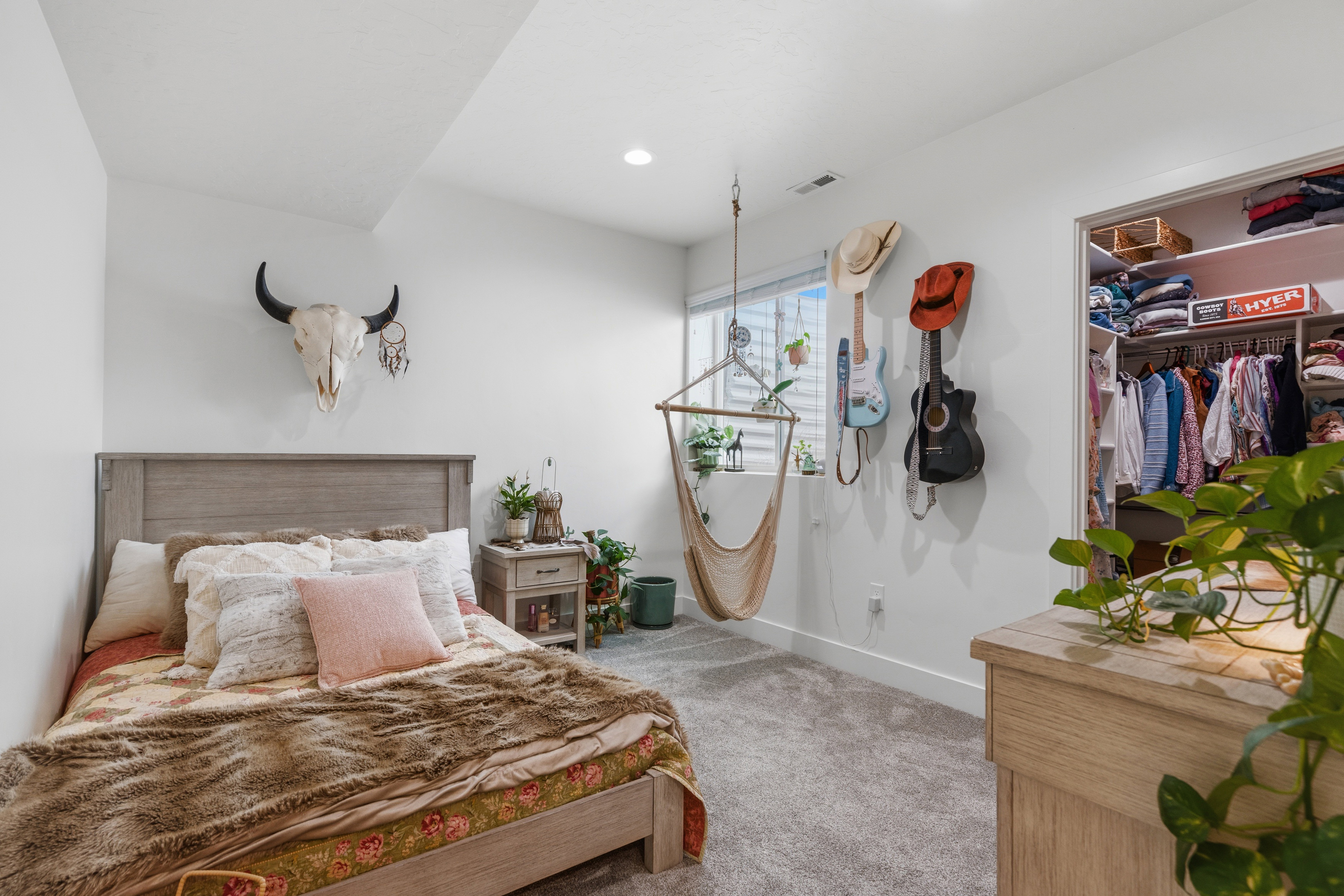 Carpeted room with a built-in closet featuring shelving and hanging rods, a single window, and a recessed ceiling light