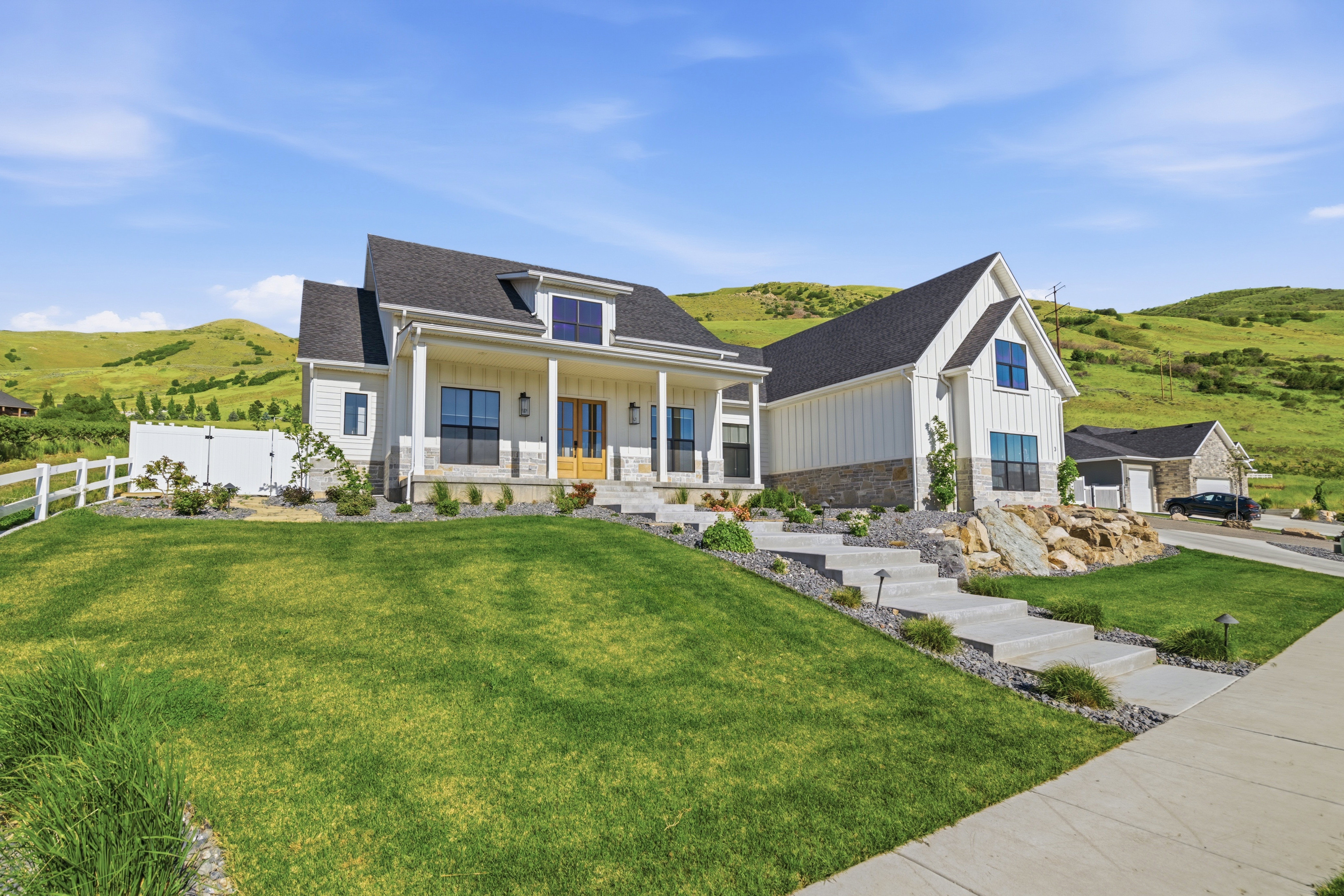 Contemporary farmhouse exterior with board and batten siding, stone accents, and a dark shingle roof
