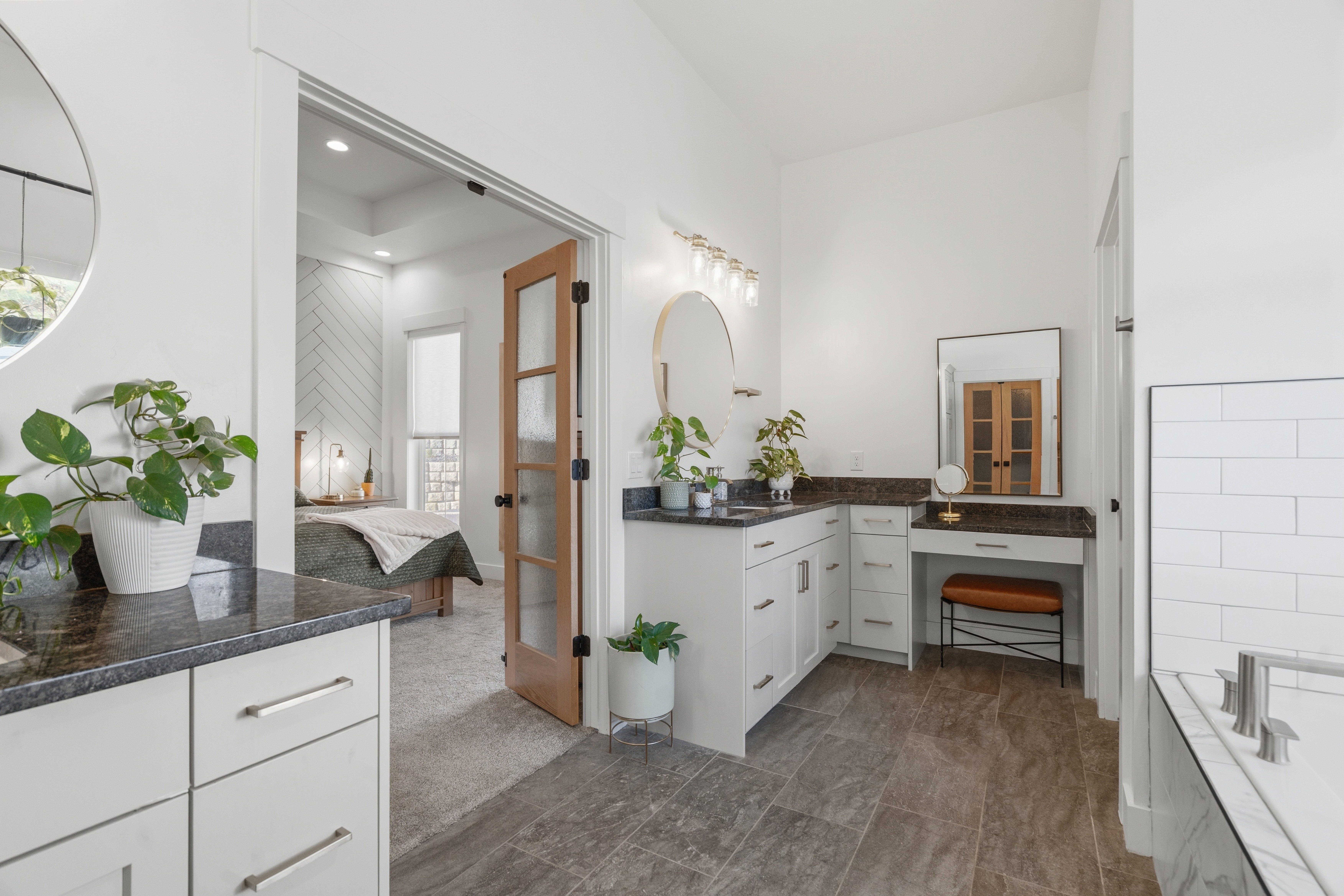 Dual vanity with dark stone countertops, white shaker cabinetry, and polished nickel hardware