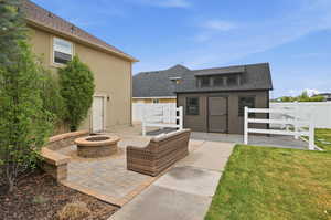 Outdoor patio featuring a stone fire pit, paver flooring, and a built-in seating wall