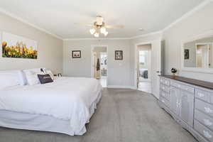 Spacious bedroom featuring light neutral wall tones, crown molding, and a ceiling fan with integrated lighting