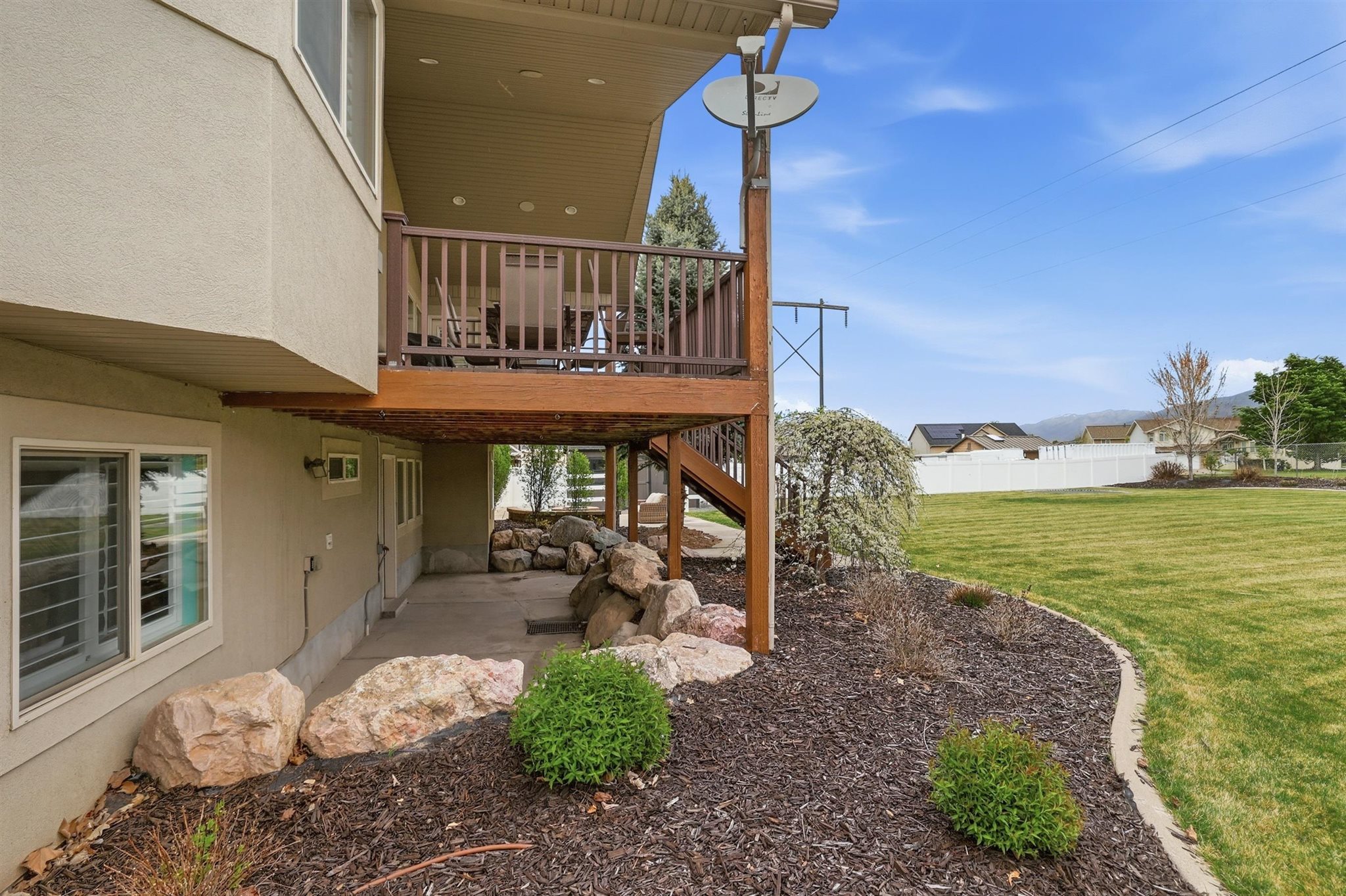 Two-story exterior featuring a private upper deck with wood railing and a covered lower patio