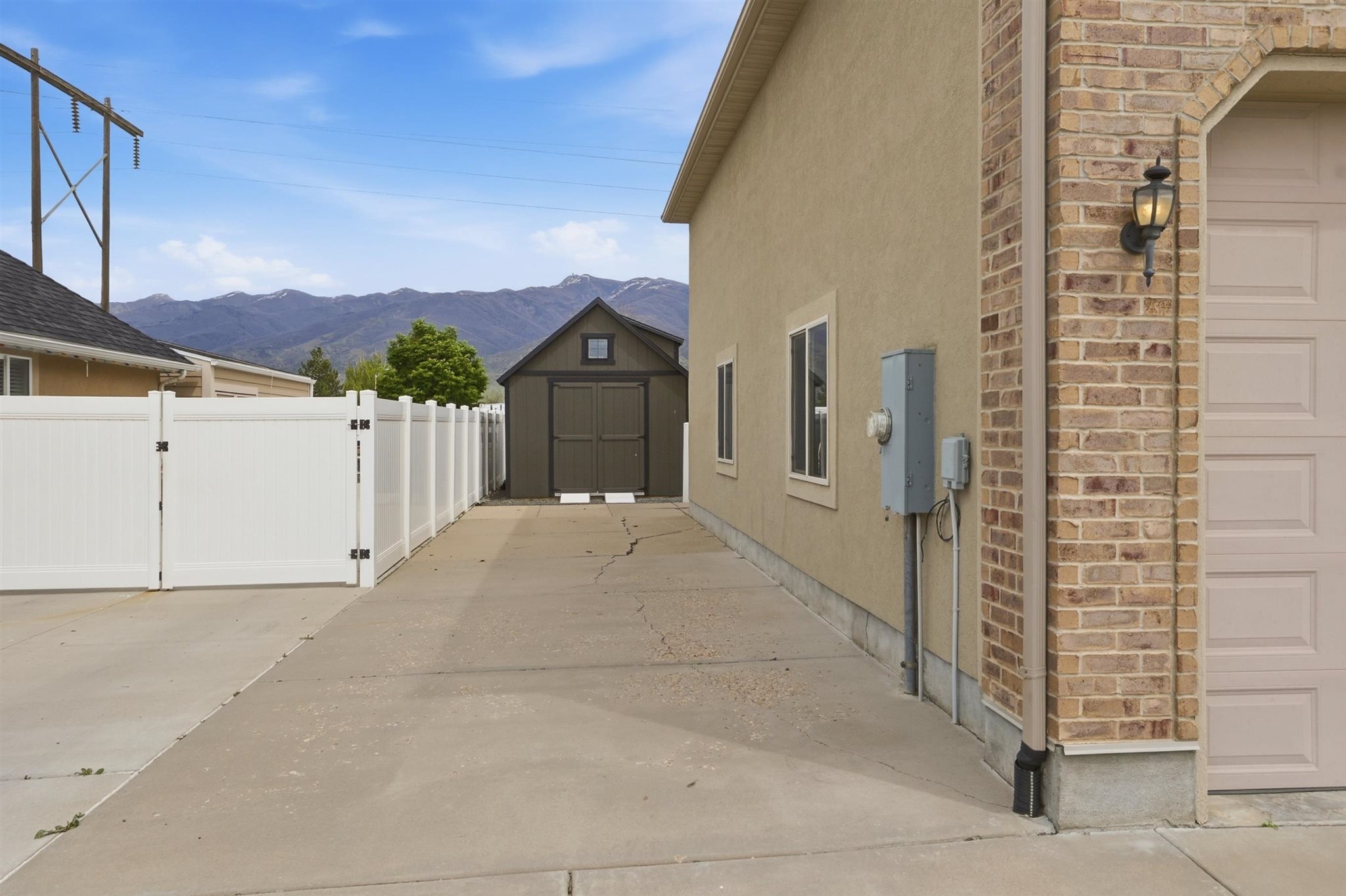 Side yard with concrete drive, white vinyl fencing, and a detached shed