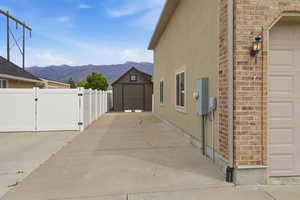 Side yard with concrete drive, white vinyl fencing, and a detached shed
