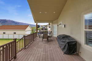 Spacious outdoor deck featuring wood-finish flooring, a full railing system, and a covered ceiling with recessed lighting